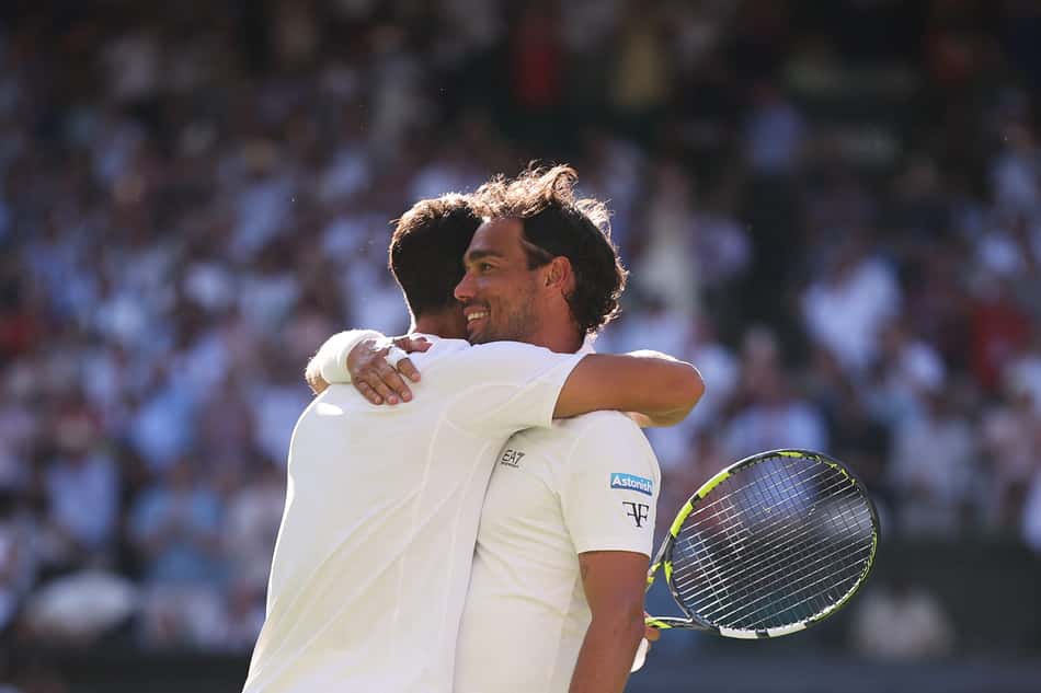 O espanhol Carlos Alcaraz (e) é abraçado pelo italiano Fabio Fognini após a vitória em Wimbledon (Foto: HENRY NICHOLLS / AFP)