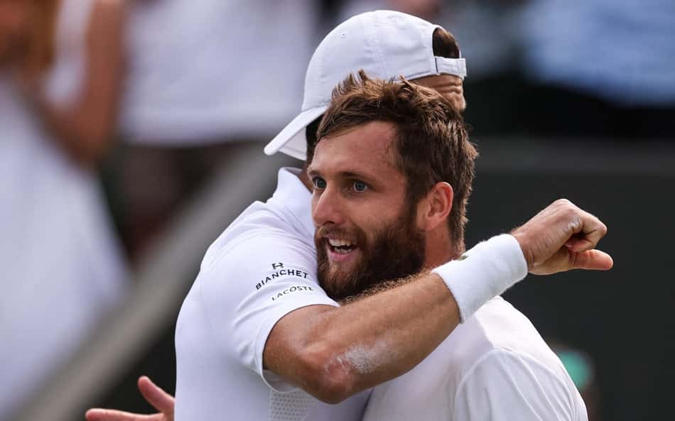 O búlgaro Grigor Dimitrov (e) abraça o francês Corentin Moutet após a vitória em Wimbledon (Fto: HENRY NICHOLLS / AFP)