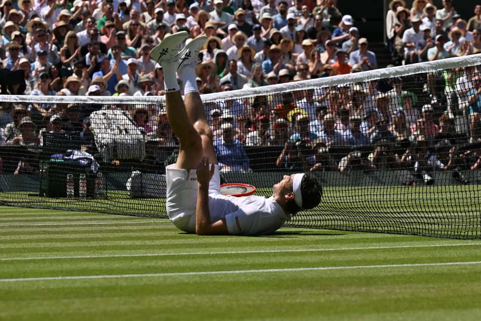 O americano Taylor Fritz escorrega na grama na partida contra o espanhol Carlos Alcaraz em Wimbledon (Foto: Glyn KIRK / AFP)