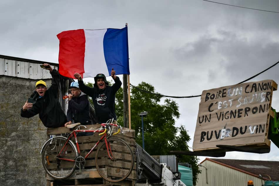 Espectadores comemoram com uma placa que diz 'beba uma taça de vinho salva um produtor de vinho, beba vinho!' ao longo do percurso (foto: Marco BERTORELLO / AFP)