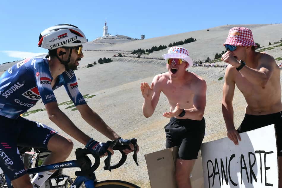 O piloto francês Valentin Paret-Peintre, da equipe Soudal Quick-Step, recebe o incentivo de dois torcedores (foto: Marco BERTORELLO / AFP)