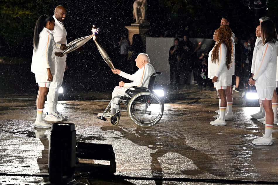 Charles Coste com a tocha olímpica nos jogos de Paris 2024 (Foto: MOHD RASFAN / AFP)