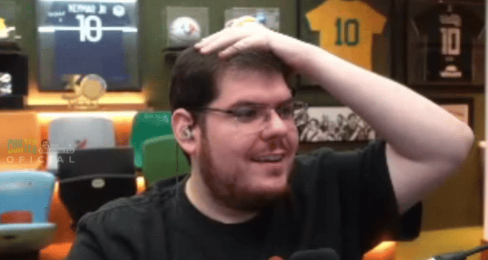 Casimiro Miguel com mão na cabeça de perfil sorrindo com o fundo do seu quarto com camisas e bolas