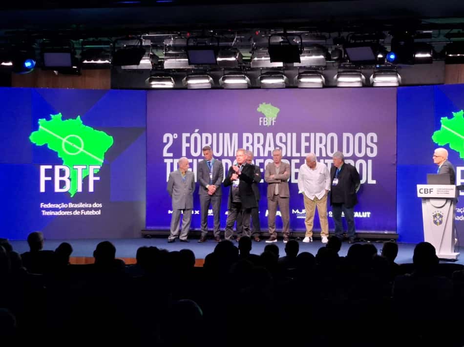 Oswaldo de Oliveira discursa em palco com Carlo Ancelotti