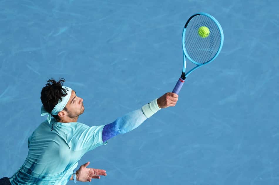 O italiano Lorenzo Musetti saca na partida contra Novak Djokovic no Australian Open (Foto: Martin KEEP / AFP)