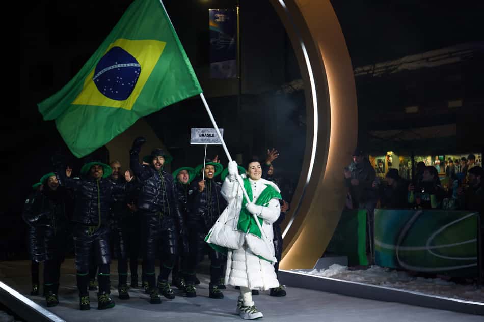 A porta-bandeira do Brasil, Nicole Rocha Silveira (D), desfila com a delegação na cerimônia de abertura dos Jogos Olímpicos de Inverno Milano Cortina 2026, em 6 de fevereiro de 2026. (Foto: Franck Fife/AFP)