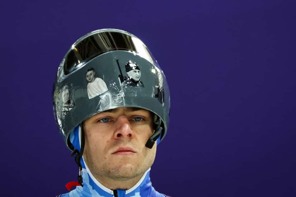 o ucraniano Vladyslav Heraskevych usa capacete com imagens de atletas vítimas da guerra com a Rússia durante treino de skeleton em Cortina. Ele foi desclassificado dos Jogos por se recusar a retirar o item. (Foto: Franck Fife/AFP)