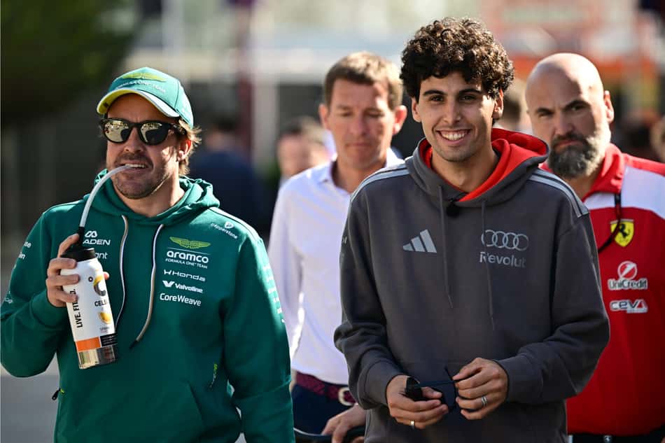O espanhol da Aston Martin Fernando Alonso e o brasileiro da Audi Gabriel Bortoleto caminham pelo paddock no primeiro dia do segundo teste de pré-temporada da Fórmula 1 no Circuito Internacional do Bahrein, em Sakhir, em 18 de fevereiro de 2026 (Foto: Giuseppe cacace/afp)