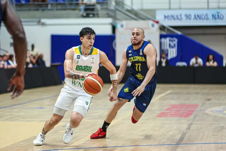 Jogador da Seleção Brasileira de basquete masculino, à esquerda, conduz a bola enquanto é marcado