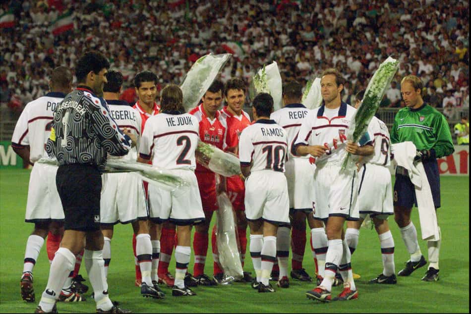 LYON, FRANÇA, 21.06.1998: ESPORTE-FUTEBOL-COPA DO MUNDO - Jogadores iranianos oferecem flores brancas e recebem rosas dos norte-americanos antes da partida que deu a vitória da seleção do Irã sobre a dos EUA (Estados Unidos) por 2x1 na Copa do Mundo de 1998. Em imagem de arquivo da Folha de S.Paulo de 22.06.1998, os atletas de ambas as equipes aparecem perfilados e reunidos no gramado do estádio, segurando buquês de flores em um gesto simbólico de paz antes do início do jogo histórico, sob os olhares do público nas arquibancadas lotadas. (Foto: Fotógrafo Não Identificado/Folhapress)