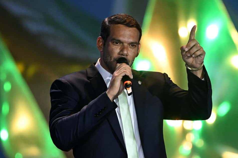 Samir Xaud, presidente da CBF, de terno com a mão para cima e falando no microfone