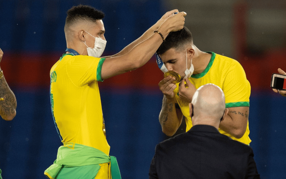 Paulinho coloca a medalha de ouro em Bruno Guimarães nos Jogos de Tóquio (Foto: Lucas Figueiredo / CBF)