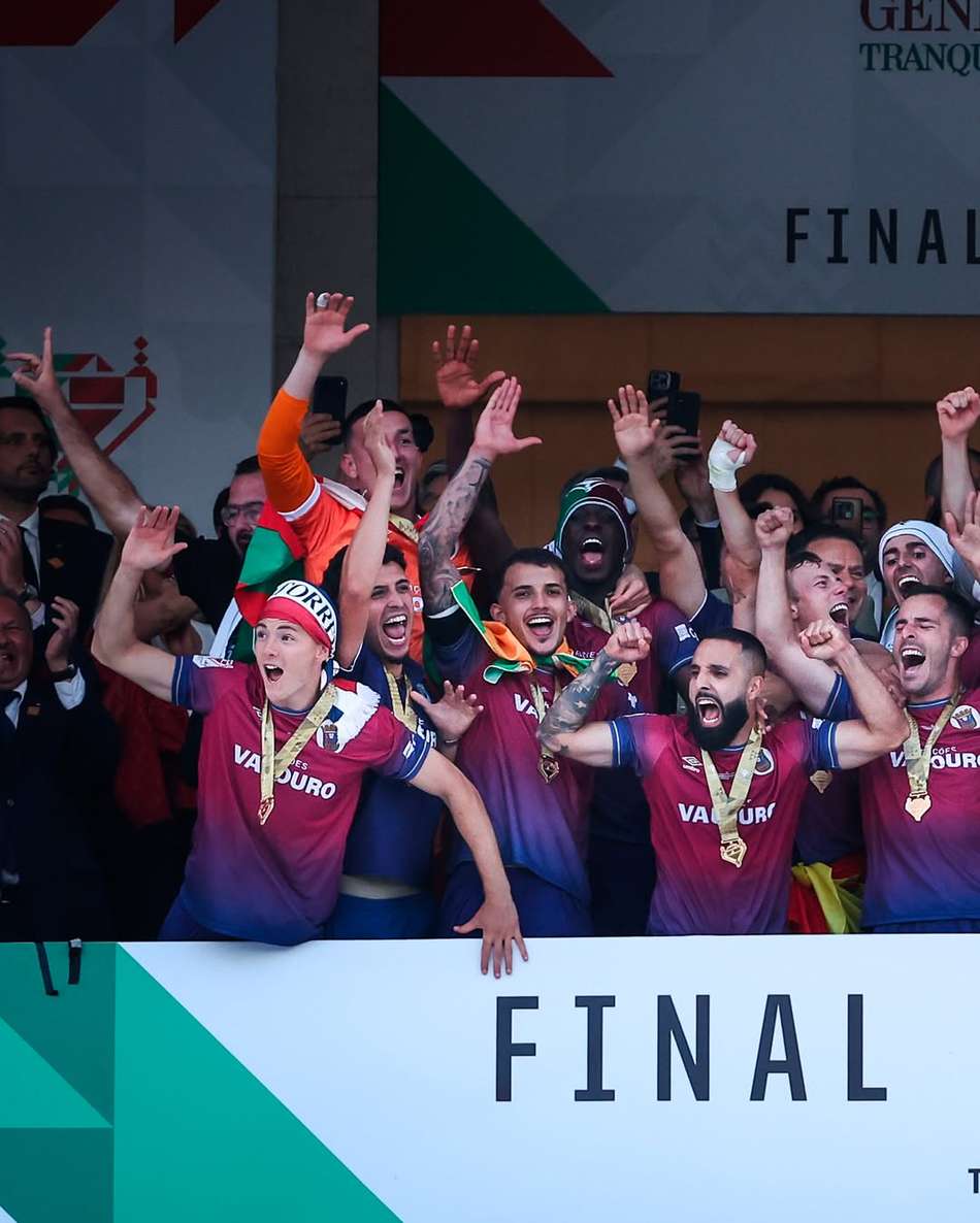 Jogadores do Torreense agrupados, utilizando o cordão da medalha do título no pescoço, com os braços erguidos para o ar comemorando o título.