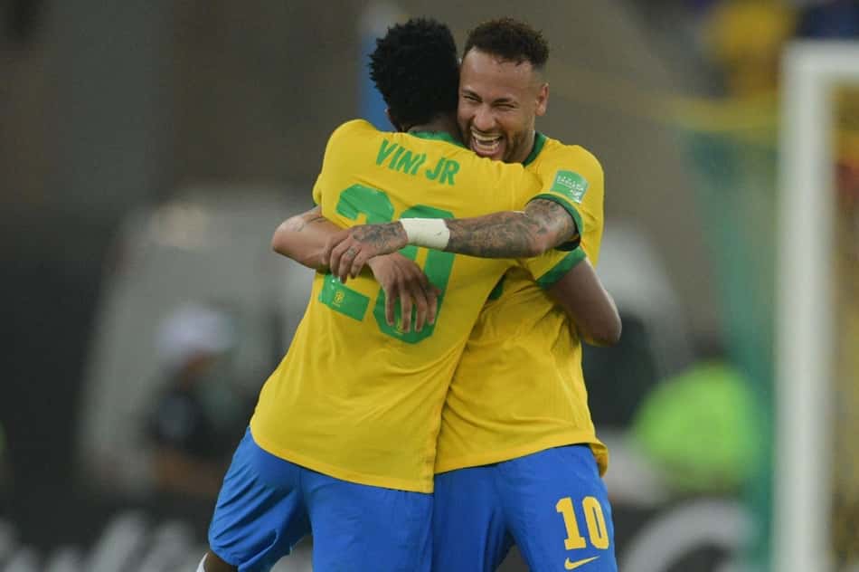 Vini Jr e Neymar se abraçam e sorriem em jogo da Seleção Brasileira