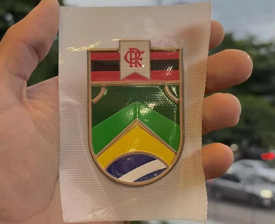 Mão segurando o patch do Flamengo em homenagem aos jogadores convocados para a Copa do Mundo.