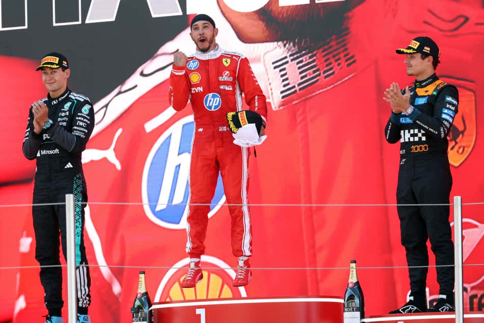 O vencedor e piloto britânico da Ferrari, Lewis Hamilton (centro), o segundo colocado e também britânico George Russell, da Mercedes (à esquerda), e o terceiro colocado, o também britânico Lando Norris, da McLaren, comemoram no pódio após o Grande Prêmio da Catalunha de Fórmula 1, no Circuito de Barcelona-Catalunha, em Montmeló, nos arredores de Barcelona (Foto: Lluis Gene / Afp)