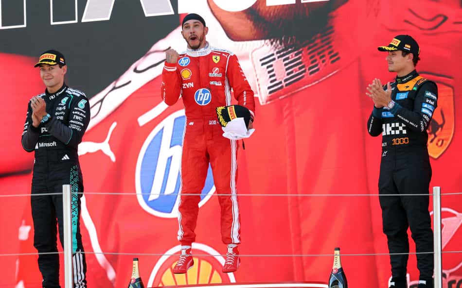 O vencedor e piloto britânico da Ferrari, Lewis Hamilton (centro), o segundo colocado e também britânico George Russell, da Mercedes (à esquerda), e o terceiro colocado, o também britânico Lando Norris, da McLaren, comemoram no pódio após o Grande Prêmio da Catalunha de Fórmula 1, no Circuito de Barcelona-Catalunha, em Montmeló, nos arredores de Barcelona (Foto: Lluis Gene / Afp)
