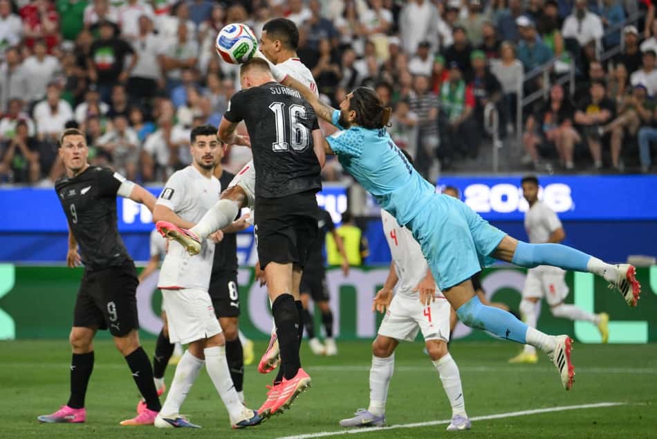 Alireza Beiranvand, goleiro do Irã, voa para disputar a bola com Finn Surman, da Nova Zelândia (Foto: Patrick T. Fallon / AFP)