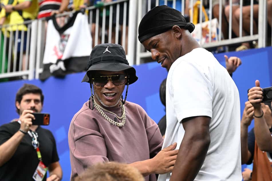 O ex-jogador de futebol brasileiro Ronaldinho (à esquerda) e o jogador de basquete norte-americano Jimmy Butler reagem antes da partida de futebol das oitavas de final da Copa do Mundo de 2026 entre Brasil e Japão, no Houston Stadium, em Houston