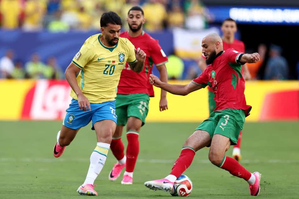 Lucas Paquetá carrega a bola, marcado por dois defensores de Marrocos
