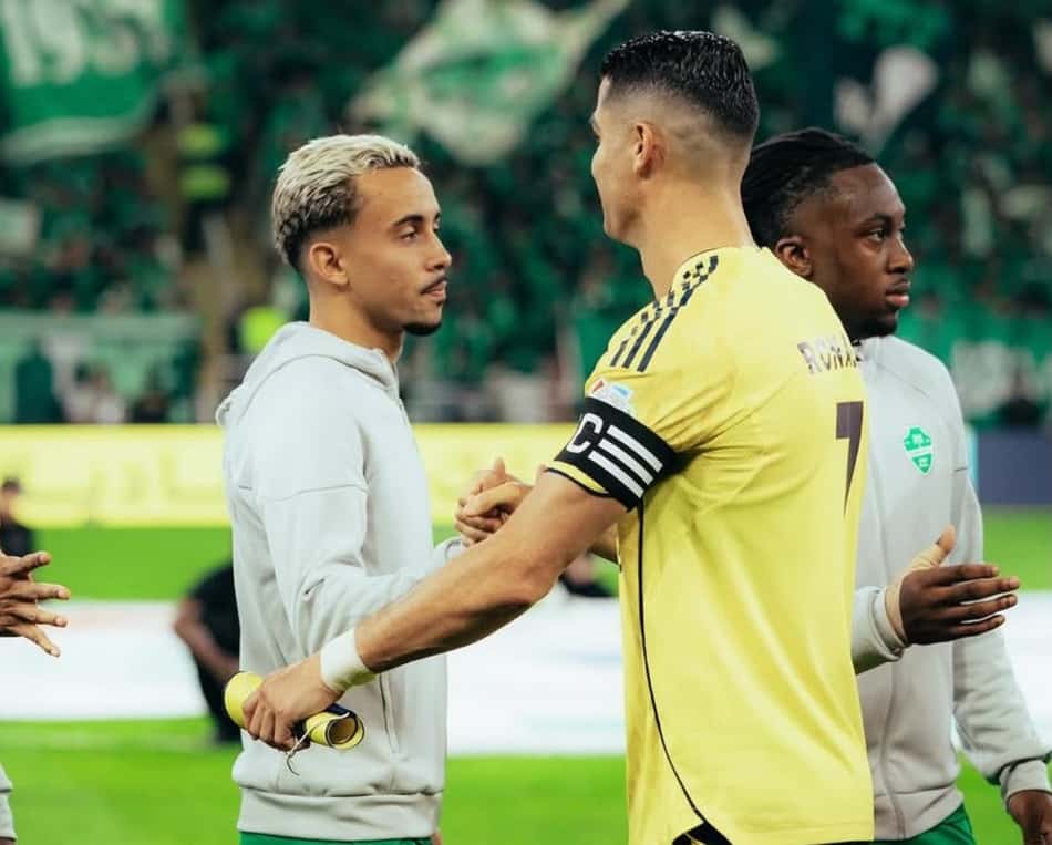 Matheus Gonçalves ao lado de Cristiano Ronaldo em partida do futebol saudita, no momento em que os jogadores das equipes se cumprimentam