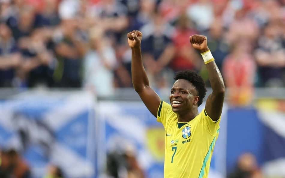 Sorridente, Vini Jr. comemora o segundo gol do Brasil sobre a Escócia na 3ª rodada da fase de grupos da Copa do Mundo com os dois braços erguidos e os punhos cerrados.