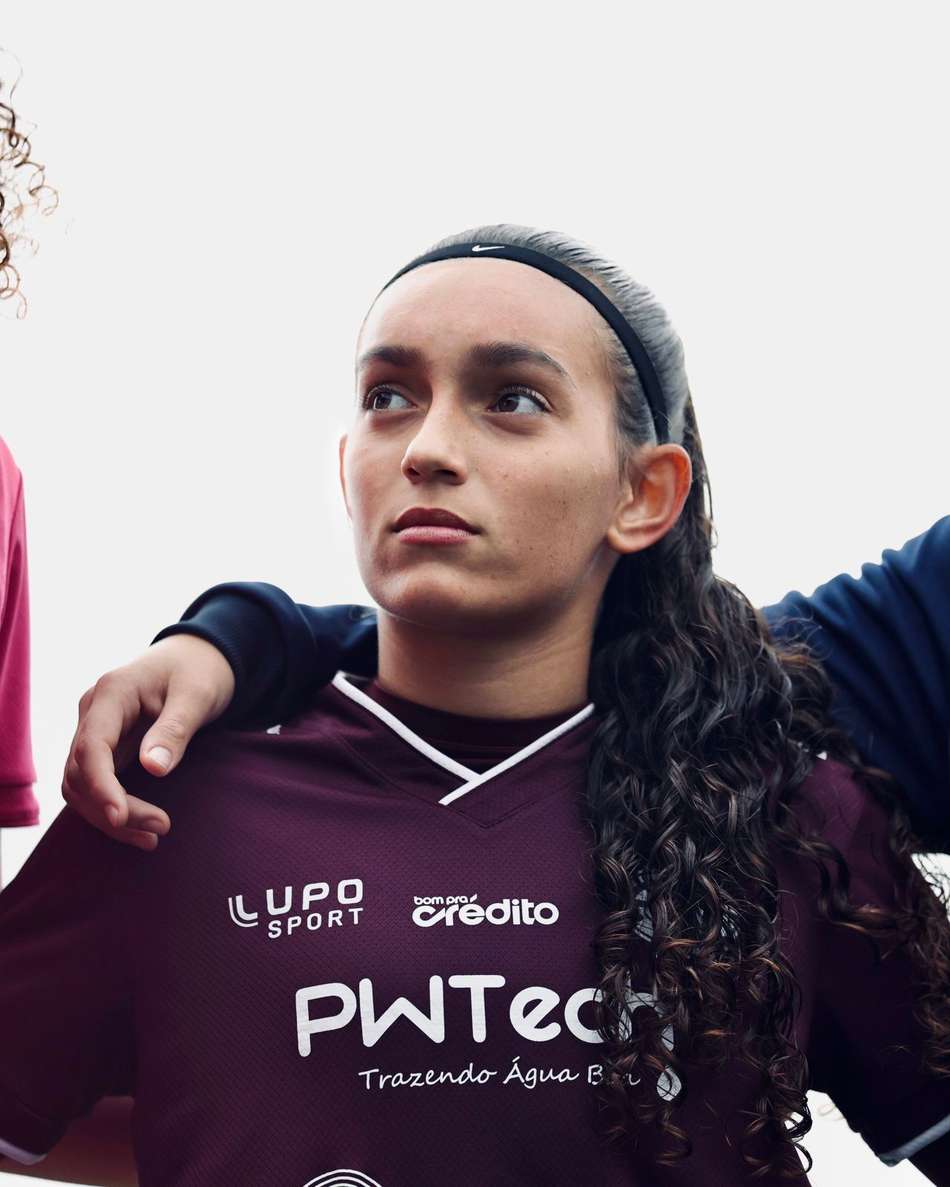 Sofia com o rosto um pouco virado com o uniforme da Ferroviária, cabelo preso e uma faixa preta na testa