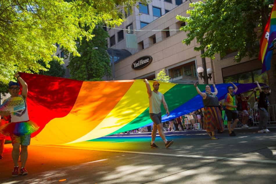 Bandeira do Orgulho LGBTQIA+ erguida por pessoas durante desfile em Seattle