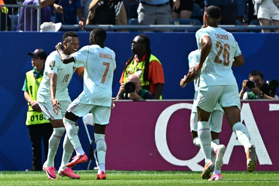 Dembélé e Mbappé, de camisas brancas, se abraçam e comemoram o terceiro gol da França contra a Noruega