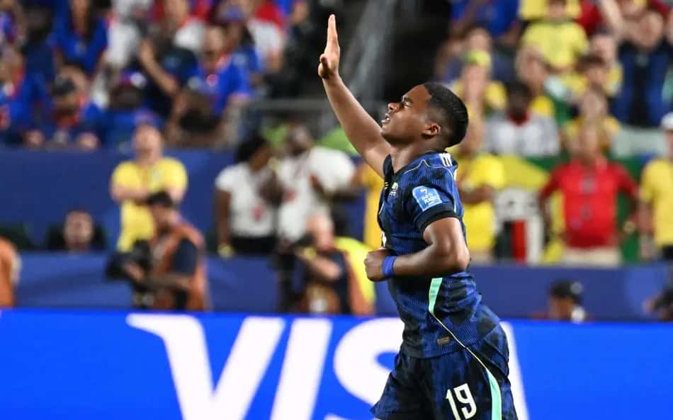 Endrick de olho fechado com a mão para cima de camisa da seleção brasileira azul