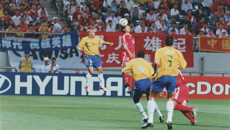 Roberto Carlos disputa bola aérea com jogador chinês