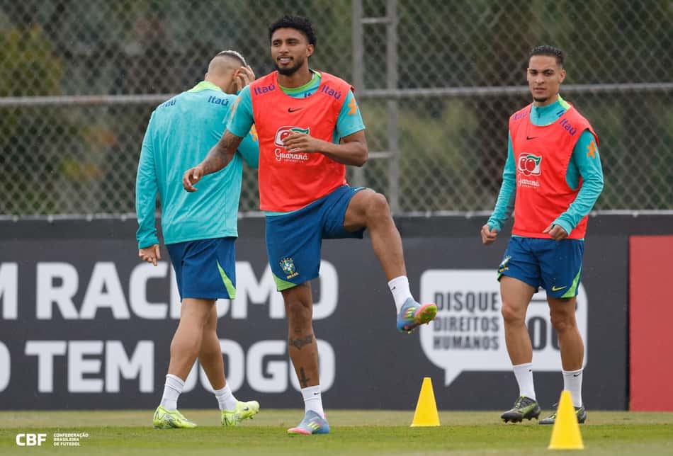 o volante Éderson se aquecendo com o colete laranja e uniforme verde de treino da seleção brasileira
