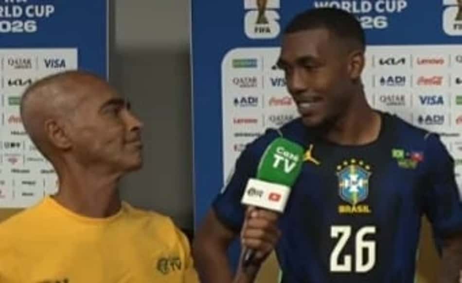 Romário, de amarelo, segura microfone da CazéTV durante entrevista com Rayan, que veste camisa azul da Seleção Brasileira