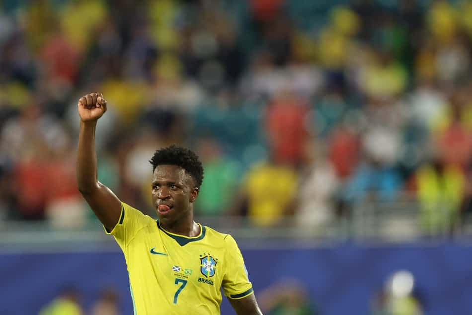 Vinicius Junior, de amarelo, levanta a mão direita em direção ao céu