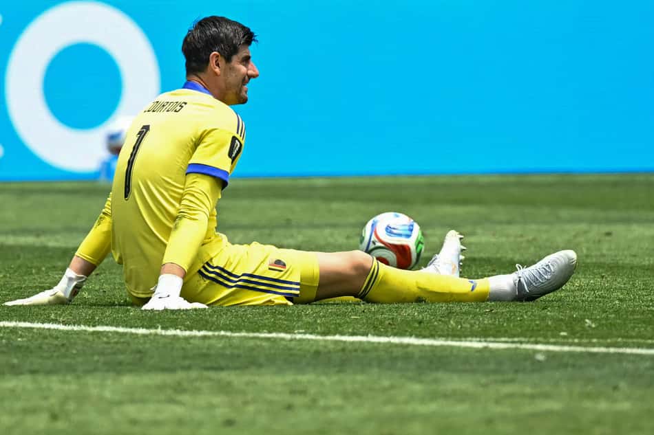 Courtois sentado em campo de uniforme amarelo