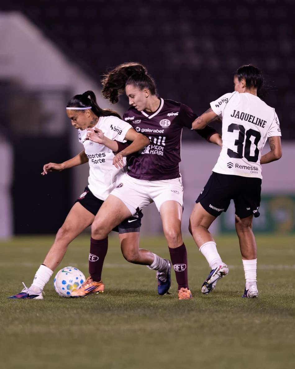 Camila entre duas jogadoras do Corinthians disputando a bola