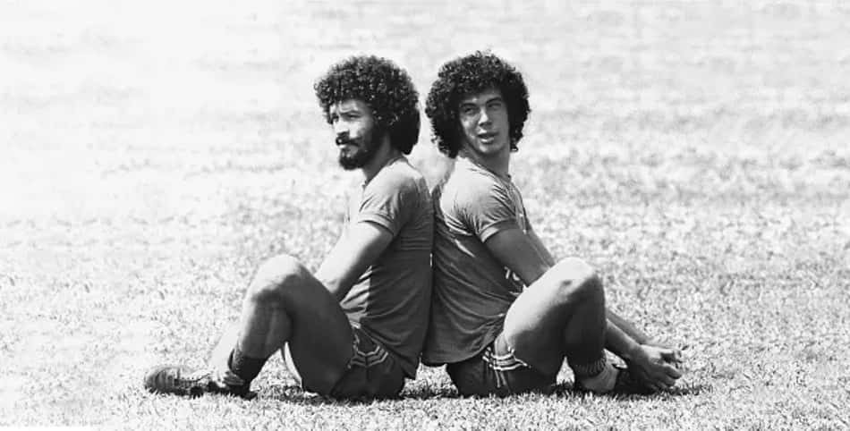 Sócrates e Walter Casagrande juntos sentados de costas um para o outro no gramado