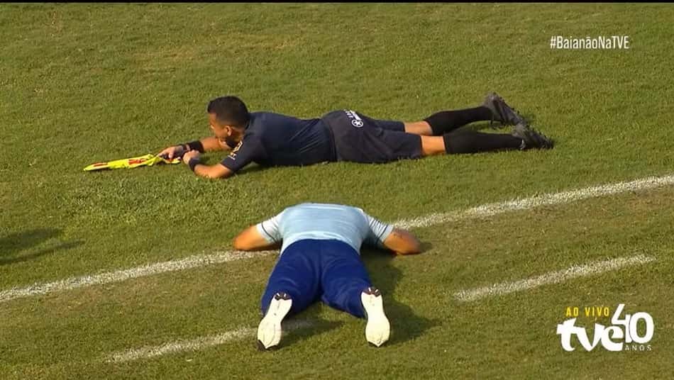 Árbitro e treinador deitados no chão do gramado