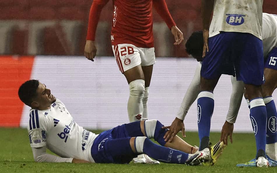 Gabriel Pec deitado no gramado com a perna sangrando durante duelo entre Cruzeiro e Internacional