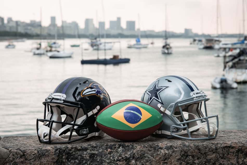 Capacetes de Ravens e Cowboys com bola de futebol americano estampada com a bandeira do Brasil na mureta da Urca, no Rio de Janeiro, palco do jogo da NFL