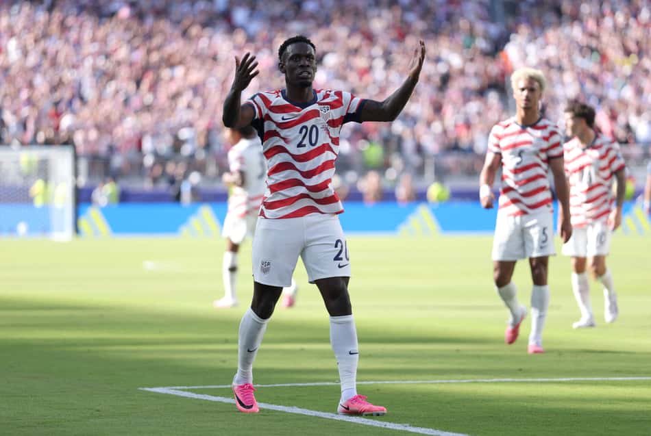 De camisa listrada nas cores vermelha e branca, Florian Bagolun, com os braços abertos, comemora o gol marcado em Estados Unidos x Bósnia pela Copa do Mundo