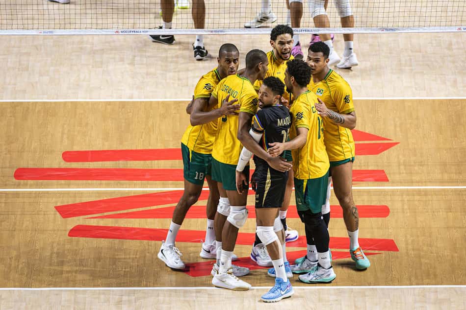 De camisas amarelas e shorts verdes, jogadores do Brasil se reúnem na quadra após marcarem ponto contra a França na VNL 2026