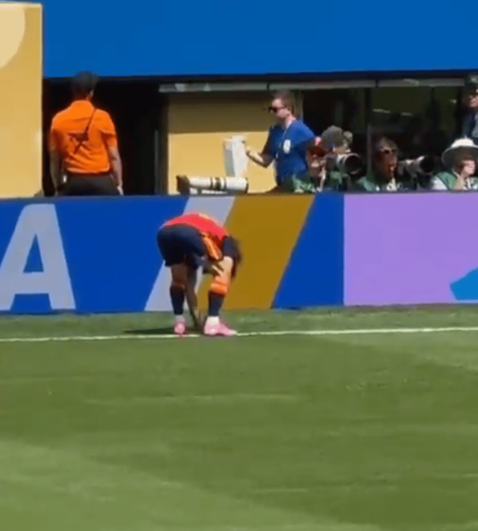 Cucurella agachado, colocando uma moeda no gramado do MetLife antes da decisão entre Espanha e Argentina.