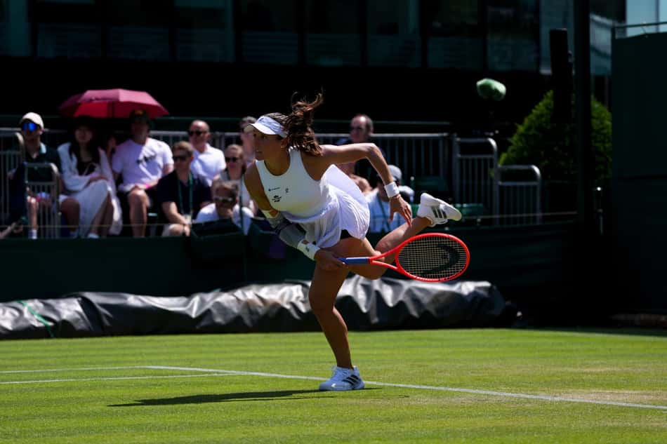 Com a perna direita no chão e a esquerda no ar, Luisa Stefani conclui movimento de saque em jogo de Wimbledon