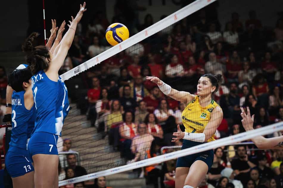De amarelo, Rosamaria ataca bola próximo à rede, com a mão direita, contra um bloqueio duplo de jogadoras da China, vestidas de azul