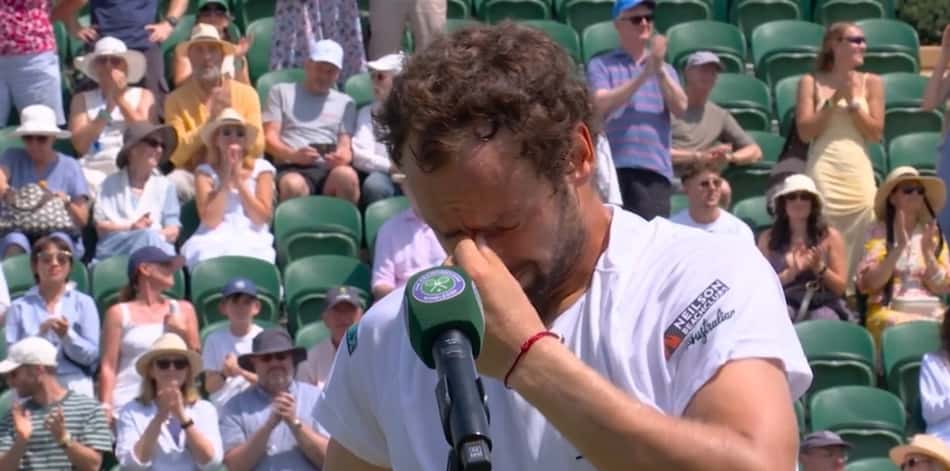 De camisa branca, Roman Safiullin leva a mão esquerda ao rosto enquanto chora durante entrevista pós-jogo em Wimbledon