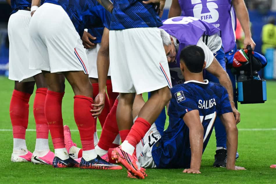 Saliba caído recebendo tratamento e cercado por jogadores da França