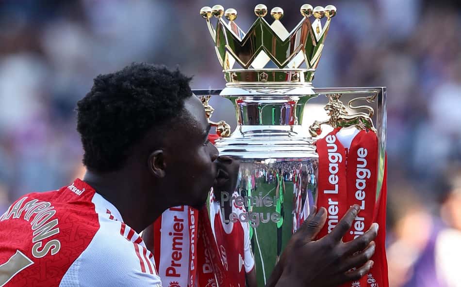 Bukayo Saka beija a taça da Premier League após o título do Arsenal