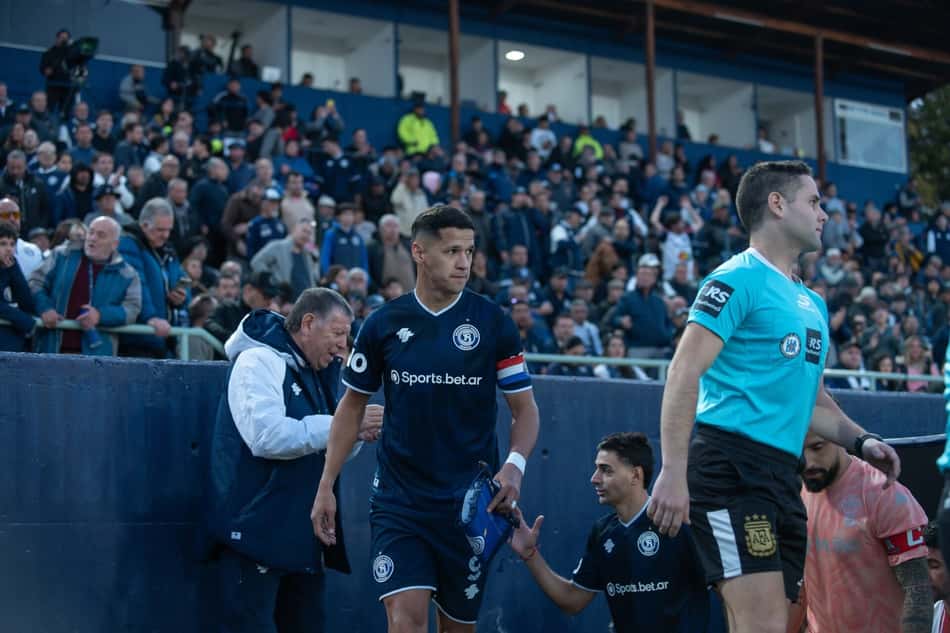 Alex Arce entrando no gramado de mãos dadas a uma criança