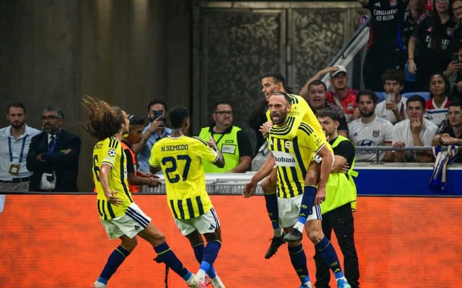 O atacante kosovar do Fenerbahçe, número 19, Vedat Muriqi (2º à direita), comemora com seus companheiros de equipe após marcar o primeiro gol do Fenerbahçe durante a partida de volta do playoff de qualificação para a Liga dos Campeões da UEFA entre Olympique Lyonnais (OL) e Fenerbahçe SK, no Estádio Groupama, em Décines-Charpieu, região centro-leste da França, em 26 de agosto de 2026.